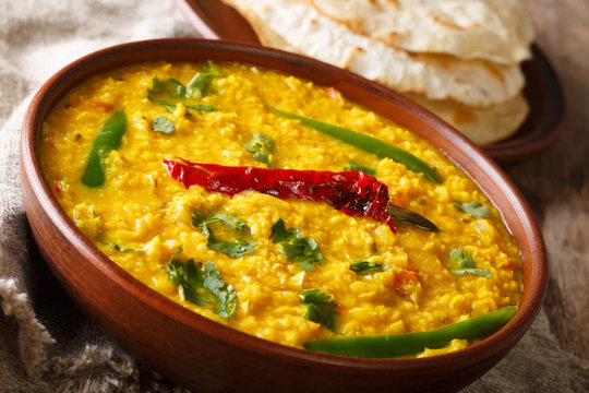 Punjabi recipe Dal Tadka vegetarian yellow lentils with spices served flat bread close up in a bowl. horizontal