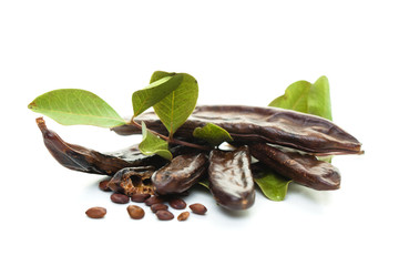 Carob on white background. Healthy organic sweet carob pods with seeds and leaves