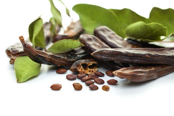 Carob bean. Healthy organic sweet carob pods with seeds and leaves on white background