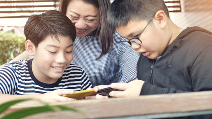 Asian family mother and son watching on mobile phone.