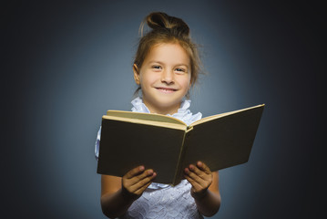 Handsome little girl with book smiling isolated on gray background