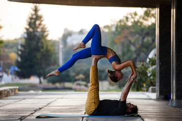 Young man and woman practicing acro yoga on street
