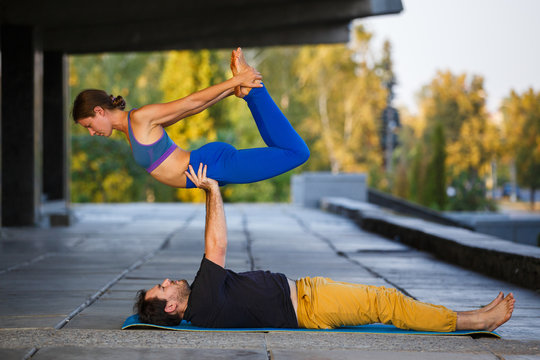 Young athletic couple practicing acroyoga. Balancing in pair. Fit