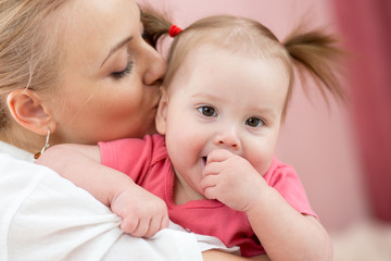 beautiful young mother kissing her adorable baby
