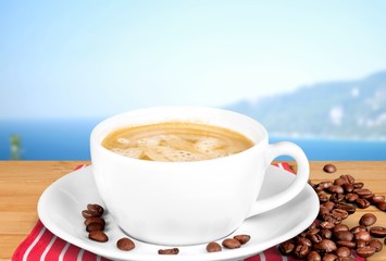 Coffee cup and coffee beans on wooden