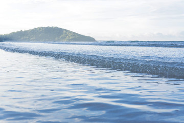 Soft wave of blue ocean on sandy beach. Background / Sand and wave at the beach background. Drop space on bottom for text and other.