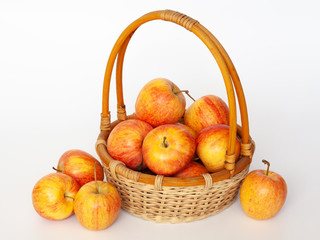 Red and yellow apples in a wicker basket. Isolated.