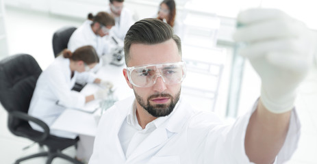 image is blurred. young scientist holding tube with the reagents