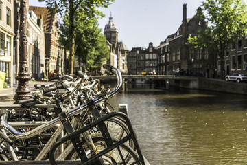 Bicycle handle bars in Amsterdam with the canal and houses in the background. There are more than...