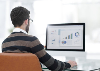 businessman analyzing graphs on computer at desk