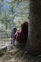 Girl sitting under a tree and thinking at sunset