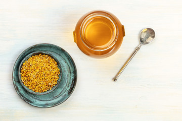 Healthy organic food. An overhead photo of pollen, a jar of honey, and a vintage spoon, shot from above on a light background with copy space