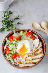 Chicken salad with egg poached in a bowl: rice, chicken, fresh vegetables and egg poached.