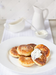 Cheese pancakes, curd cheese pancakes in cast iron frying pan on white background