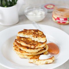 Cheese pancakes, curd cheese pancakes in cast iron frying pan on white background