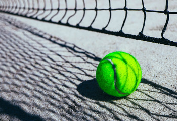One green tennis ball on court, sport competition concept. Tennis net shadow on the ball. Macro...