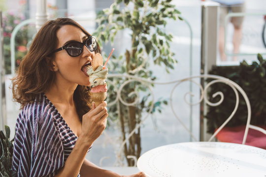 Portrait of beautiful happy woman eating (licking) melting artisanal hand made organic ice-cream in Italian cafe - traveling and healthy Mediterranean food (cuisine) concept - picture with copy space