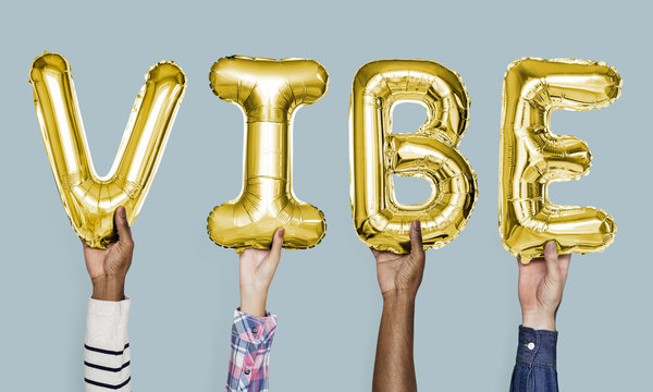 Yellow gold alphabet balloons forming the word vibe
