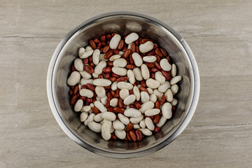 Fototapeta na wymiar legumes - a source of protein and micronutrients: red and white beans in a metal plate on the table, in the center; a vegetarian diet and a healthy lifestyle.