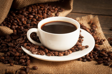Coffee cup and beans on a rustic background. Coffee Espresso and a piece of cake with a curl. Cup of Coffee and coffee beans on table.