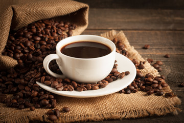 Coffee cup and beans on a rustic background. Coffee Espresso and a piece of cake with a curl. Cup of Coffee and coffee beans on table.