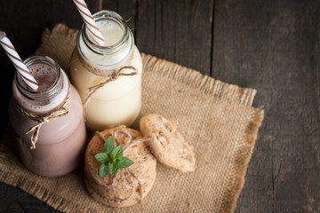 Photo of fresh Made Chocolate Banana Smoothie on a wooden table with cookies, banana and coconut. Milkshake. Protein diet. Healthy food concept. Drink, coffee beans, chocolate.
