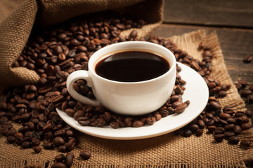 Coffee cup and beans on a rustic background. Coffee Espresso and a piece of cake with a curl. Cup of Coffee and coffee beans on table.