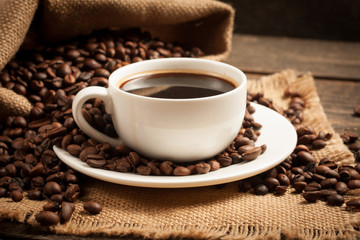 Coffee cup and beans on a rustic background. Coffee Espresso and a piece of cake with a curl. Cup of Coffee and coffee beans on table.