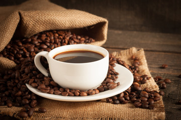 Coffee cup and beans on a rustic background. Coffee Espresso and a piece of cake with a curl. Cup of Coffee and coffee beans on table.