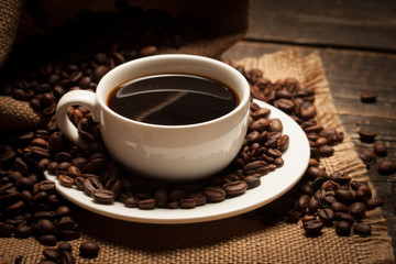 Coffee cup and beans on a rustic background. Coffee Espresso and a piece of cake with a curl. Cup of Coffee and coffee beans on table.