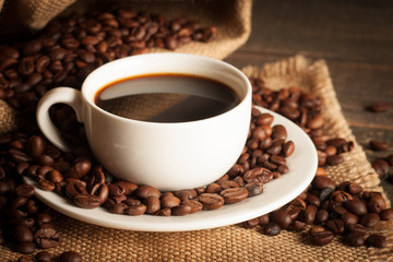 Coffee cup and beans on a rustic background. Coffee Espresso and a piece of cake with a curl. Cup of Coffee and coffee beans on table.