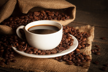 Coffee cup and beans on a rustic background. Coffee Espresso and a piece of cake with a curl. Cup of Coffee and coffee beans on table.