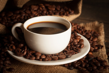 Coffee cup and beans on a rustic background. Coffee Espresso and a piece of cake with a curl. Cup of Coffee and coffee beans on table.