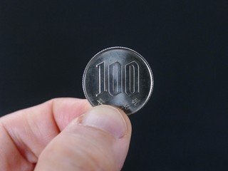 close up photo of hand holding 100 yen on the dark background. The Japan Financial concept. 