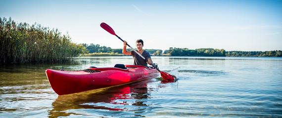 Portrait of man kayaking on idyllic lake using paddle