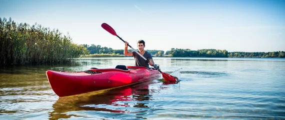 Foto op Canvas Portrait of man kayaking on idyllic lake using paddle © Kzenon