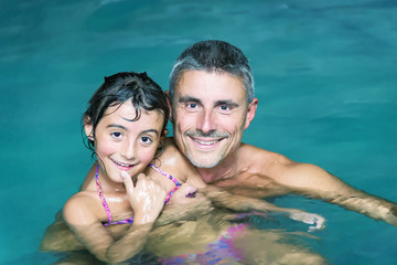 Happy father and daughter relaxing in a pool at night