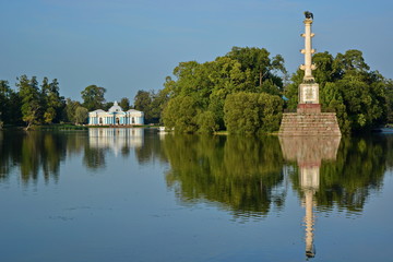 Monument chesme column and pavilion grotto with reflection at blue water on big lake in catherine...