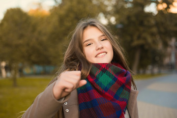 Portrait of a beautiful girl in park. Teenage girl with colorful scarf and brown coat. Close up photo. Young student have fun. Lifestyle photo. beautiful hair.