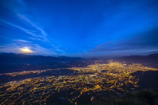 Aerial of Grenoble at night with moon rising over the mountains