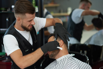 Fototapeta na wymiar Professional barber shaving face of client with razor.