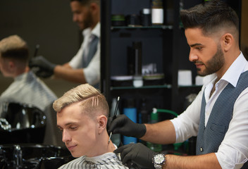 Bearded barber shaving neck of client using razor.