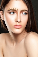 Obraz premium Beautiful woman portrait with golden brows and golden beads on face.