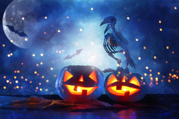 Halloween holiday concept. Pumpkins over wooden table at night scary, haunted and misty forest.