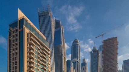 View of modern skyscrapers shining in sunrise lights timelapse in Dubai Marina in Dubai, UAE.