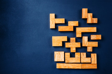 Different geometric shapes wooden blocks arrange in solid figure on a dark background. Creative, logical thinking and problem solving concept. Copy space