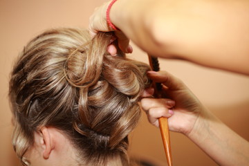 Fototapeta premium Hairdresser doing hairstyle for young woman . The concept of the wedding.