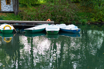 Obraz premium Empty boats in a row in the calm water of a pond or lake in autumn.