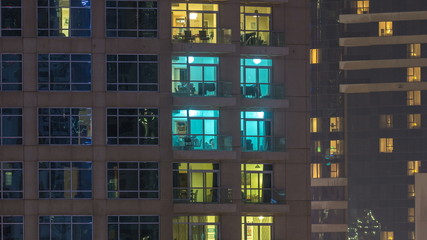 Windows of the multi-storey building of glass and steel lighting inside and moving people within timelapse