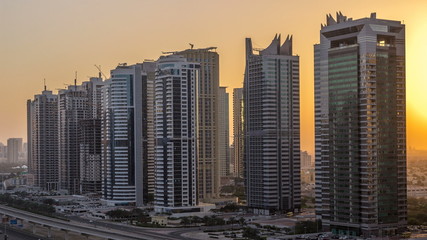 Aerial view of Jumeirah lakes towers skyscrapers night to day timelapse with traffic on sheikh zayed road.